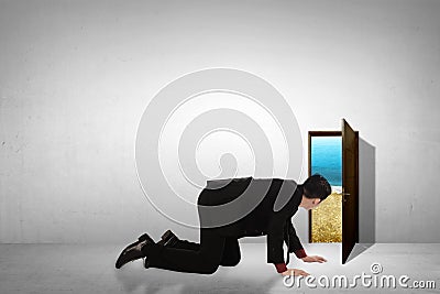 Business man take peek on small door through beach Stock Photo