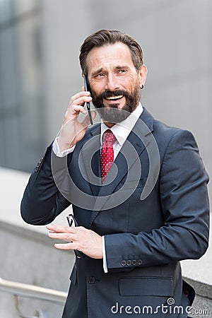 Business man talking active with the client on a cell phone out of office building. Handsome bearded manager outdoor makes call Stock Photo