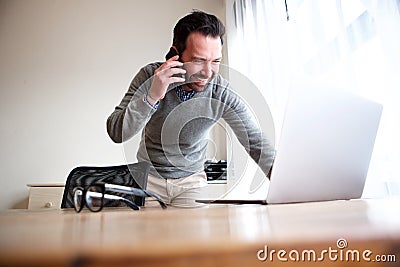 Business man talking on mobile phone and looking at computer Stock Photo