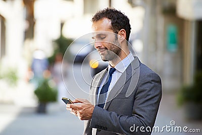 Business man typing sms on mobile phone in street Stock Photo