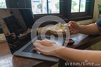 Business man using laptop computer, hand typing notebook keyboard and eating fast food French fries with ketchup..Sedentary Stock Photo