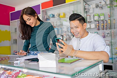 a business man using a smartphone and a business woman using a calculator Stock Photo