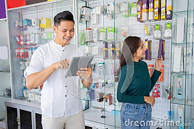 business man using a tablet with a woman choosing mobile phone accessories products Stock Photo