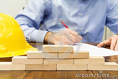 Business man and wall built with small wooden blocks Stock Photo