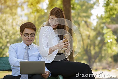 Business man and woman are interested in working on his laptop while relaxing in the park Stock Photo