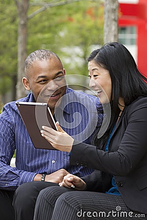 Business man and woman outside on their break with their tablets Stock Photo