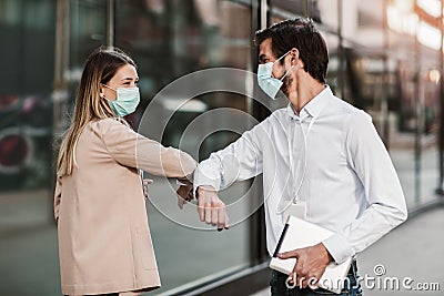 Business man and woman with safety masks greeting with elbow bump Stock Photo