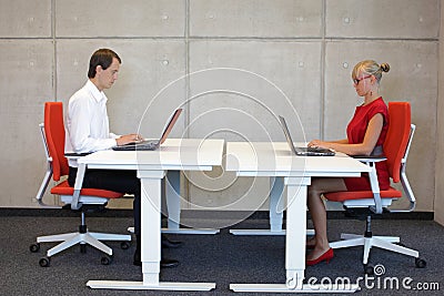 Business man and woman working in correct sitting posture with laptops sitting on chairs Stock Photo