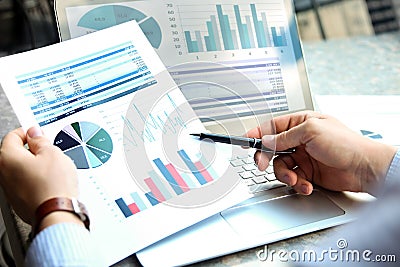 Business man working and analyzing financial figures on a graphs on a laptop outside Stock Photo