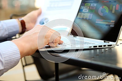 Business man working and analyzing financial figures on a graphs on a laptop outside. Stock Photo