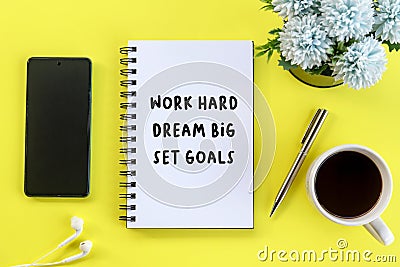 Business Monday motivational words - Work hard, dream big, set goals. With text on book, ear phone, coffee cup, pen and flowers. Stock Photo
