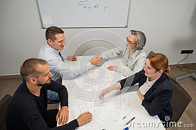 Business partners shake hands. Four business people are negotiating in the conference room. Stock Photo