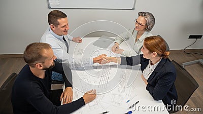 Business partners shake hands. Four business people are negotiating in the conference room. Stock Photo