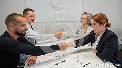 Business partners shake hands. Four business people are negotiating in the conference room. Stock Photo