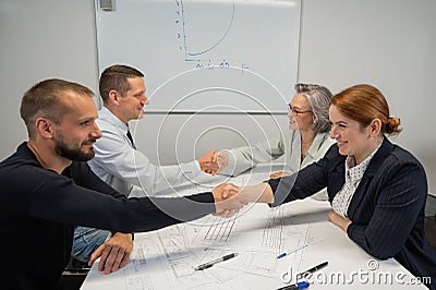 Business partners shake hands. Four business people are negotiating in the conference room. Stock Photo