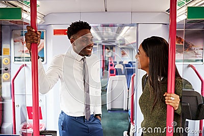 Business Passengers Standing In Train Commuting To Work Having Discussion Stock Photo