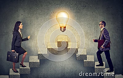 Business people climbing stepping up a stairway career ladder with idea light bulb on a top Stock Photo