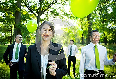 Business People Holding Green Balloon In Forest Stock Photo