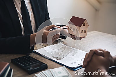 Business people home sales broker is using a pen pointing to the house model and describing the various components of the house Stock Photo