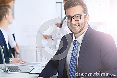 Business people at meeting in office. Focus at cheerful smiling bearded man wearing glasses. Conference, corporate Stock Photo