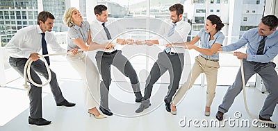 Business people playing tug of war in office Stock Photo