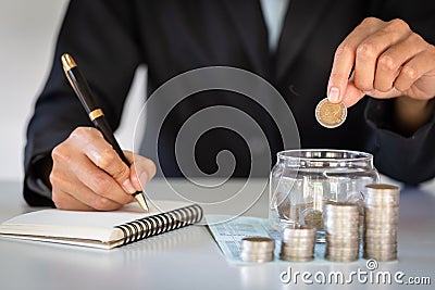 Business people put coins in glass bottles. Record income and there are ladders arranged in rows. Concept of saving money, Stock Photo