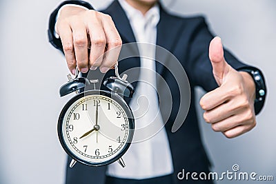Business people thumbs up with alarm clock for punctual good time or best timing concept Stock Photo