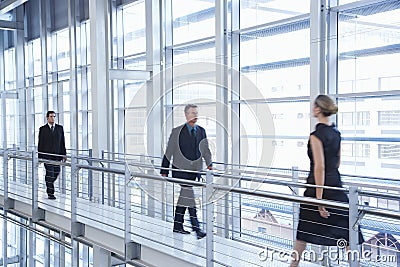 Business People Walking By Railing In Modern Office Stock Photo