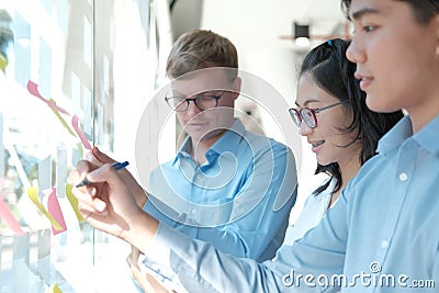 Business people working planning discussing idea with sticky reminder note on glass wall Stock Photo