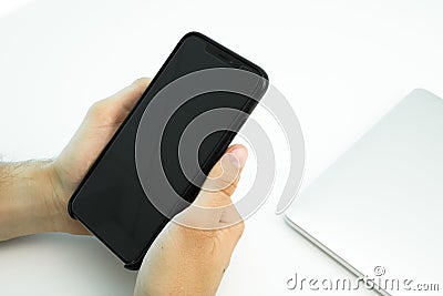 Business person using his smartphone on a white table. Modern workplace. Laptop Stock Photo