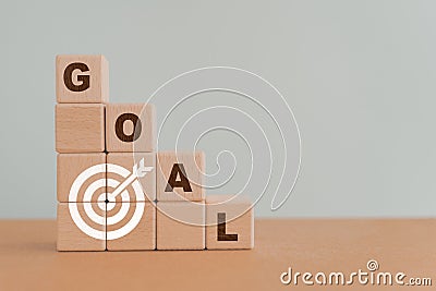 Business or personal achievement goal and objective target concept. GOAL word and white dartboard icon on step of wooden cube Stock Photo