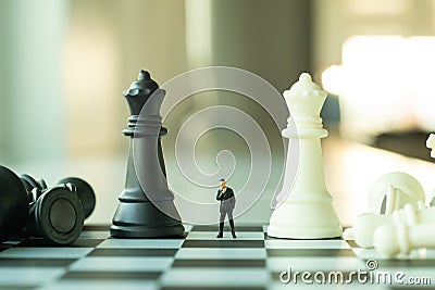 Business planning concept. Small businessman figure standing and walking on chessboard with chess pieces Stock Photo