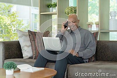 Business senior old elderly Black American man, African person using a smartphone or mobile phone in living room at home in Stock Photo