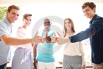 Business, startup and office concept - happy creative team showing thumbs up in office. Stock Photo