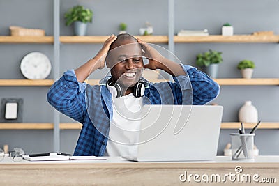 Business success and luck. Excited black businessman looking at laptop computer and touching head in excitement Stock Photo