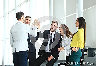 Happy successful multiracial business team giving a high fives gesture as they laugh and cheer their success Stock Photo