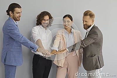 Business team of happy young entrepreneurs standing together and joining their hands Stock Photo