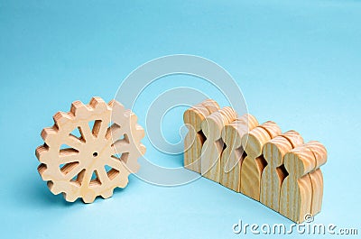 Business team stands near the wooden gear. Concept business idea. Teamwork. strategy, cooperation. Interaction and unity. The Stock Photo