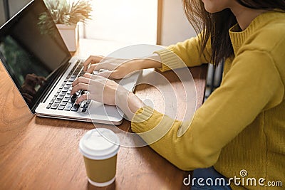Digital lifestyle working outside office. Woman hands typing laptop computer with blank screen on table in coffee shop. Stock Photo