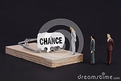 Figures of businessmen stand near a mousetrap, the bait in which is torn paper with the inscription - CHANCE Stock Photo