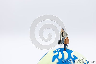 Business Travel and Global Concept. Close up of businessman traveler miniature figure with baggage running on mini world ball on Stock Photo