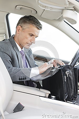 Businessman searching in bag while sitting in car Stock Photo