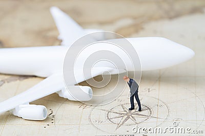 Business trip planning or travel concept, miniature adult businessman looking at compass on vintage world map with toy Stock Photo