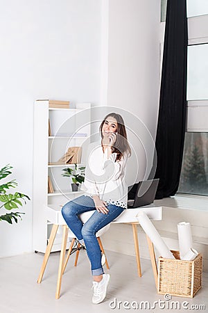 Business vumen. Young girl working in the office. The girl calls on the phone and sits on the table. Calling customers of the comp Stock Photo