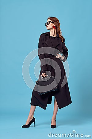 Business woman in black coat wearing sunglasses professional elegant style blue background Stock Photo