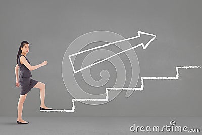 Business woman climbing stairs against grey background with white arrow Stock Photo