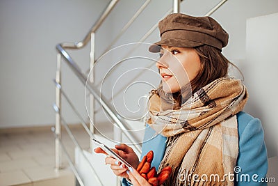 Business woman in coat stands on the stairs in the mall with smartphone. Shopping. Fashion Stock Photo