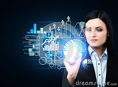 A business woman in formal suit is pushing out the element on the hologram with business icons. Stock Photo