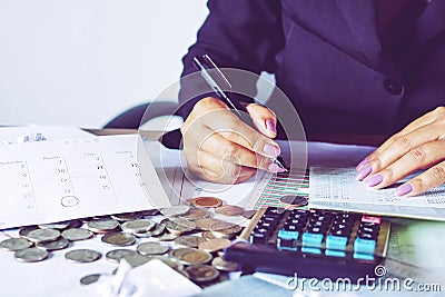 Business woman hand calculating her monthly expenses during tax season with coins, calculator, credit card and account bank Stock Photo