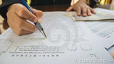 Business woman hand hold pen fill in the details on the tax forms paper in business concept. Stock Photo